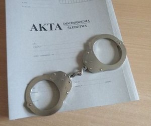 Na zdjęciu teczka na policyjne akta, na których leżą kajdanki.