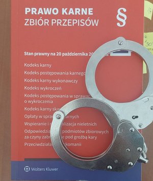 Na zdjęciu kodeks karny na którym leżą policyjne kajdanki.