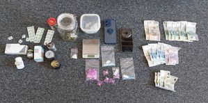 Na zdjęciu zabezpieczone narkotyki i tabletki, pieniądze, waga do ważenia, szklane słoiczki z substancjami.