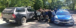 Na zdjęciu policjanci, radiowóz, leśnicy z samochodem straży leśnej i dzieci.