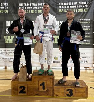 Na zdjęciu w środku ml. asp. Damian Grendys. Obok niego na podium zawodnicy.