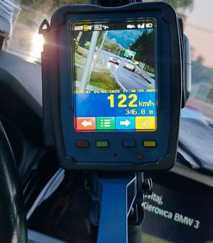 Na zdjeciu wyświetlacz ręcznego miernika prędkości z zarejestrowanym pojazdem, który przekroczył dopuszczalną prędkość i jechał 122 km/h, na drodze z ograniczeniem do 50 km/h.