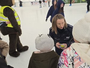 Na zdjęciu policyjny miś POPO, policjantki oraz dzieci korzystające z lodowiska.