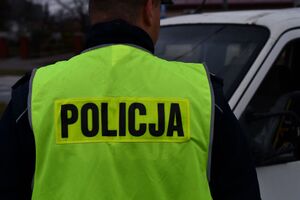 Na zdjęciu tyłem umundurowany policjant, w blaskowej kamizelce z napisem policja na plecach.