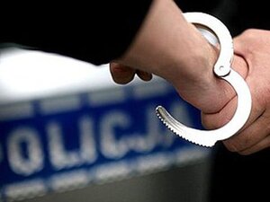 ręce w kajdankach, w tle napis policja