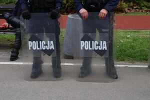 Na zdjęciu umundurowani policjanci z tarczami służbowymi z napisem policja.