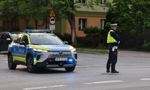Na zdjęciu umundurowani policjant ruchu drogowego, obok radiowóz.