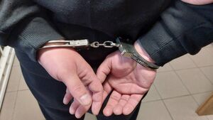 Na zdjeciu męskie dłonie, na które założone są kajdanki.