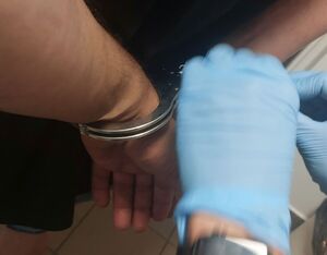 Na zdjęciu na ręce zakładane są kajdanki.