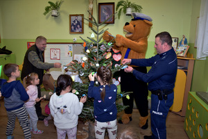 POLICJANT Z DZIEĆMI UBIERAJĄCY CHOINKĘ