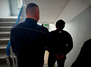 policjant, w tle zatrzymany mężczyzna