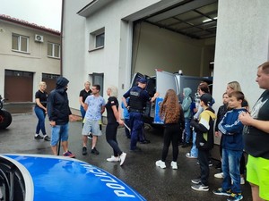 Uczestnicy spotkania przy siedzibie krośnieńskich strażaków. Na pierwszym planie przednia część radiowozu z napisem policja