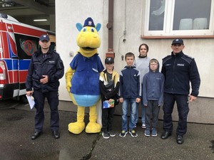 Funkcjonariusze oraz policyjna maskotka na zdjęciu z dziećmi