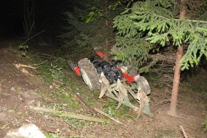 Przewrócony ciągnik rolniczy w zagłębieniu terenu przy drodze gruntowej