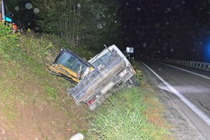 dostawcze iveco przewożące koparkę w przydrożnym rowie