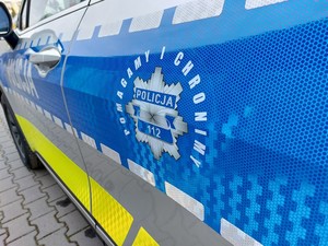 boczna część radiowozu z hasłem Pomagamy i chronimy na niebieskim tle drzwi pojazdu