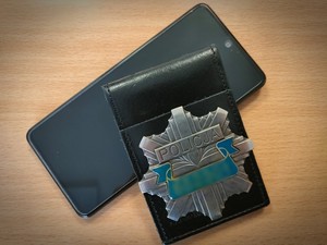 leżący na biurku telefon i policyjna odznaka