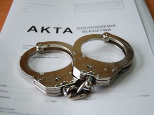 kajdanki ułożone na teczce akt sprawy