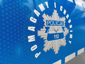 hasło pomagamy i chronimy oraz grafika policyjnej gwiazdy na niebieskim tle drzwi radiowozu