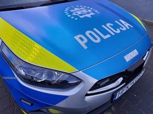 przednia część radiowozu z napisem policja i grafiką policyjnej gwiazdy z hasłem pomagamy i chronimy