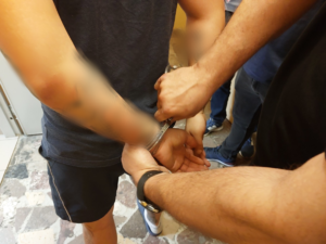 Policjant zakłada kajdanki zatrzymanemu mężczyźnie