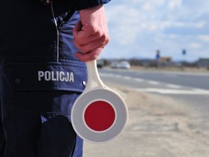 policjant trzymający w ręce tarczę służącą do wydawania sygnałów do zatrzymywania pojazdów