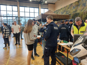 uczniowie i odzwiedzający stoisko policyjne, na zdjęciu widoczni funkcjonariusze i inne osoby