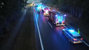 policjanci oraz strażacy na zablokowanej drodze