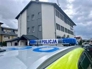 Na zdjęciu widać belkę na radiowozie z napisem POLICJA, w tle budynek Komendy Powiatowej Policji w Brzozowie
