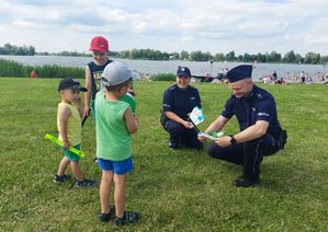 Policjanci rozmawiają z dziećmi na brzegu zbiornika wodnego