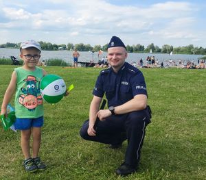 Policjant z chłopcem na brzegu zalewu