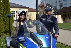 Dziewczyna na policyjnym motocyklu. Obok stoi policjant