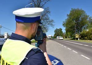 Policjant dokonuje pomiaru prędkości przejeżdżającym pojazdom