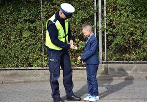 Policjant wręcza chłopcu odblask