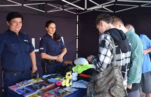 Policjantki na policyjnym stoiku. Przy stoisku stoją chłopcy.