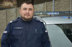 Umundurowany policjant na tle radiowozu