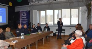 Debata dla seniorów. Na sali znajdują się osoby starsze, policjanci i prelegenci.