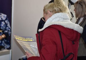Kobieta czyta ulotkę promująca pracę w policji