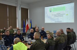 Sala konferencyjna na której znajdują się przedstawiciele służb mundurowych i osoby cywilne