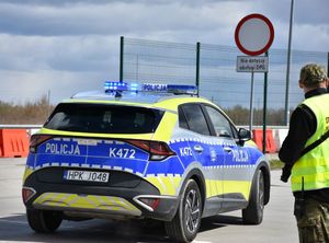Radiowóz na przejściu granicznym. Obok niego funkcjonariusz SG