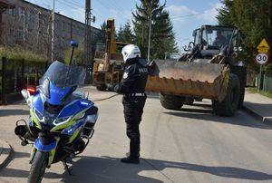 Policjant kieruje ruchem. Obok niego policyjny motocykl