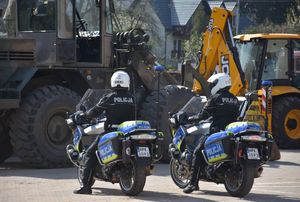 Policjanci na motocyklach. W tle koparki