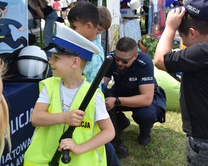 Chłopiec ubrany w kamizelkę i policyjną czapkę