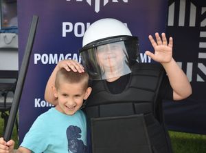 Chłopiec w policyjnym umundurowaniu. Obok niego chlopiec
