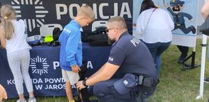 Policjant ubiera chłopcu element policyjnego umundurowania
