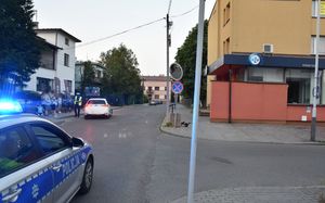 Miejsce zdarzenia drogowego. Na zdjęciu widoczna jest część radiowozu oraz policjant wykonujący oględziny miejsca zdarzenia.