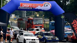 Zdjęcie przedstawia uczestników imprezy motoryzacyjnej na stracie. W tle wóz strażacki