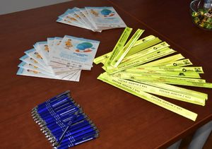 Upominki dla dzieci rozłożone na stole - odblaski, książeczki i długopisy