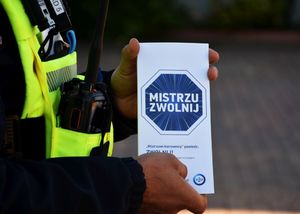 Policjant trzyma ulotkę Akcji Mistrzu Zwolnij