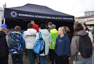 Policyjne stoisko profilaktyczne przy którym znajduje się młodzież